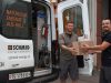 Vor einem Schmid Servicebus übergibt ein Lagermitarbeiter einem Servicemitarbeiter ein Paket mit Ersatzteilen.