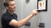 Mann bedient Steuerung PersonalTouch visio auf digitalem Display an einem elektronischen Schaltschrank, um die Holzheizung zu bedienen.